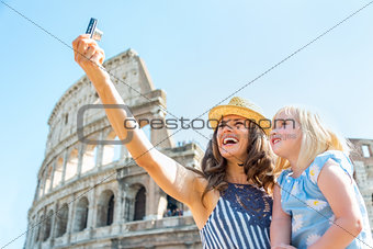 Happy mother and baby girl making selfie in front of colosseum i