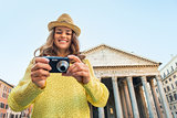 Portrait of happy young woman checking photos in camera in front
