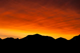 Flaming red sunrise with mountain silhouette
