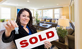 Hispanic Woman with Keys and Sold Sign in Living Room
