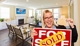 Young Woman Holding Sold Sign and Keys Inside Living Room