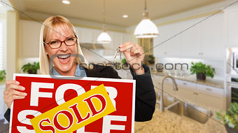 Young Woman Holding Blank Sign and Keys Inside Kitchen
