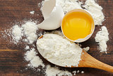 wooden baking background with raw eggs and flour