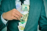 man in suit putting bills in his jacket, depicting concepts such