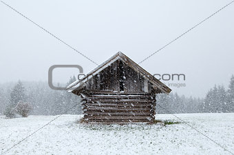 wooden old hut at snowfall