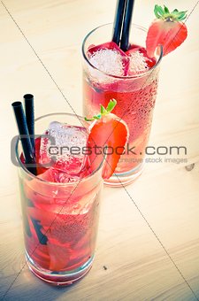 glasses of strawberry cocktail with ice on old wood table, old style