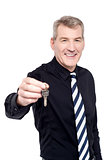 Male realtor showing the keys to camera
