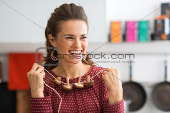Portrait of happy young housewife using mushrooms on string as n