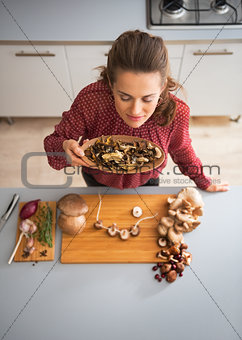 Young housewife smelling dried mushrooms