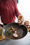 Closeup on young housewife cooking mushrooms in kitchen