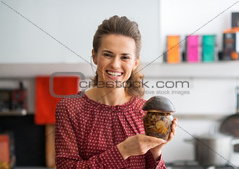 Portrait of happy young housewife showing jar of pickled mushroo