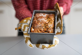 Closeup on young housewife showing baking dish with bread