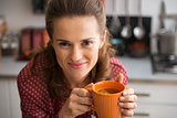 Portrait of happy young housewife drinking tea in kitchen