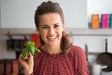 Portrait of happy young housewife showing fresh basil