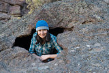 A young woman smiling from a hole in a boulder
