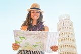 Portrait of smiling young woman with map in front of leaning tow