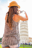 Young woman taking photo of leaning tower of pisa, tuscany, ital