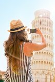Young woman taking photo of leaning tower of pisa, tuscany, ital