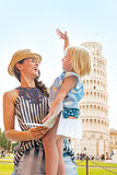 Happy mother and baby girl with map in front of leaning tower of