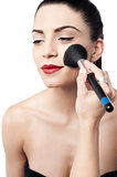 Pretty woman applying makeup with brush