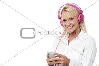 Smiling woman enjoying music with her mobile phone