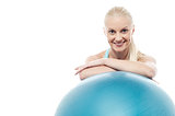Woman in gym relaxing beside exercise ball