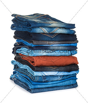 high stack of colored jeans on a white background