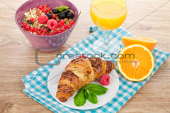 Healthy breakfast with muesli, berries, orange juice and croissa