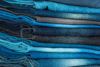 stack of different shades of blue jeans as a background