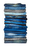 high stack of various shades of blue jeans on a white background