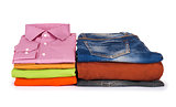 stack of colorful shirts, sweaters and jeans on a white backgrou