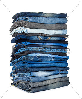 high stack of various shades of blue jeans on a white background