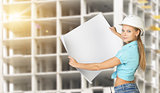 Woman holding blank drawing sheet in front of building under construction