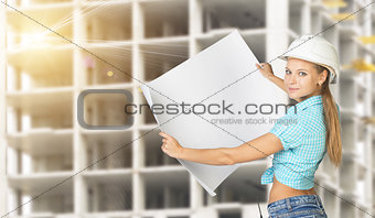 Woman holding blank drawing sheet in front of building under construction