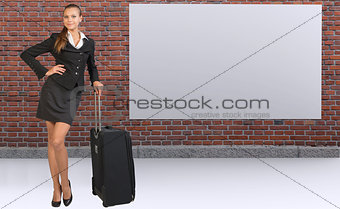 Businesswoman with travel bag against brick wall