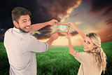 Composite image of attractive young couple hanging a frame