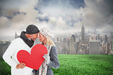 Composite image of smiling couple in winter fashion posing with heart shape