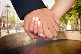 Composite image of newlyweds holding hands close up