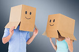 Composite image of couple wearing emoticon face boxes on their heads