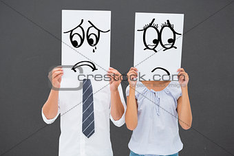 Composite image of couple holding paper over their faces