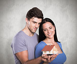 Composite image of young couple holding a model house