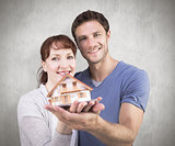 Composite image of couple holding a model house