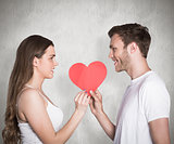 Composite image of romantic young couple holding heart