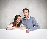 Composite image of happy young couple with blank board