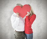 Composite image of couple embracing and holding heart over faces