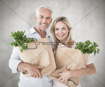 Composite image of happy couple carrying paper grocery bags