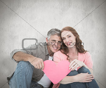 Composite image of casual couple holding pink heart