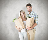 Composite image of attractive couple holding their grocery bags