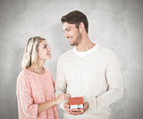 Composite image of attractive couple holding miniature house model