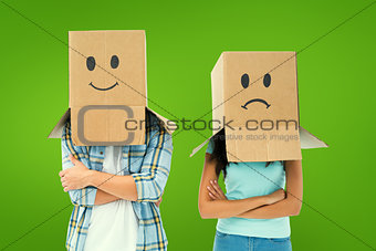 Composite image of young couple wearing sad face boxes over head